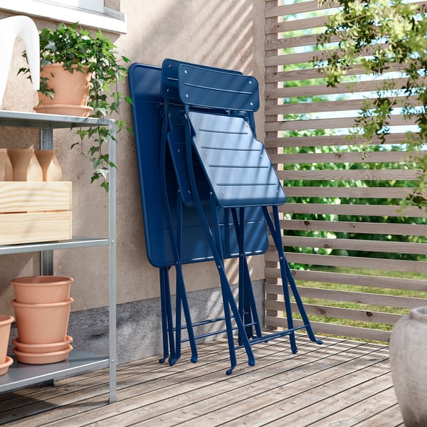 Blue SUNDSÖ chairs stacked on balcony with plants.