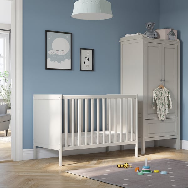Nursery a white SUNDVIK cot, tall grey storage unit, and framed wall art on blue walls.