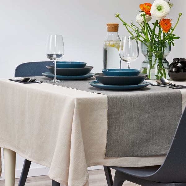 Table set with blue bowls and wine glasses, featuring a grey table runner, creating a stylish dining scene.
