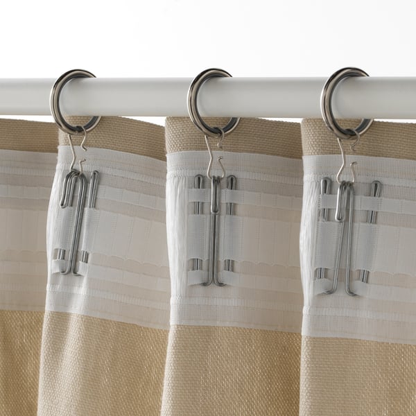 Beige curtains hang from silver hooks on white rod.