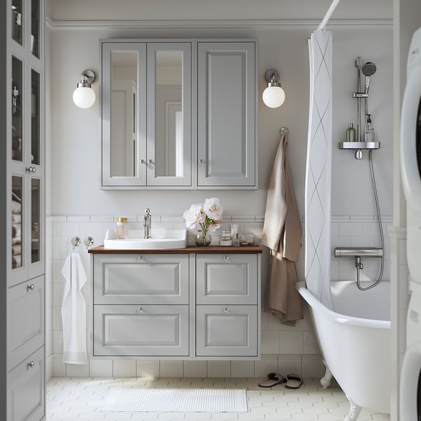 Modern grey bathroom with mirror cabinets, white sink, freestanding tub, semi-recessed basin, wall-mounted vanity, soft lighting, sleek fixtures.