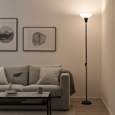 A living room with a light gray sofa, black floor lamp taller than other items, coffee table, and wall art.