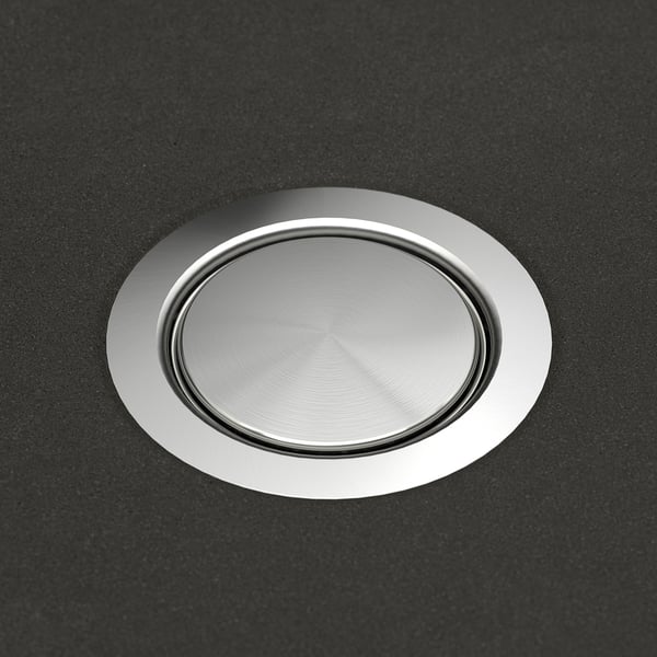 Round, stainless steel sink drain cover with a smooth, polished surface set in a sleek black countertop.