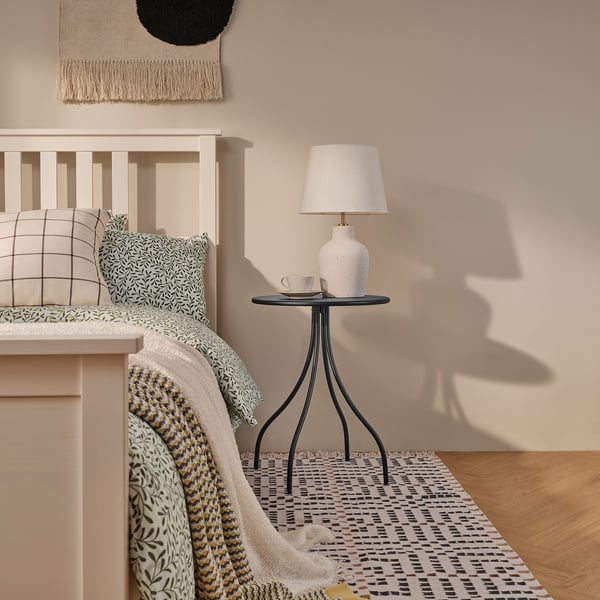 Anthracite side table with lamp beside bed.