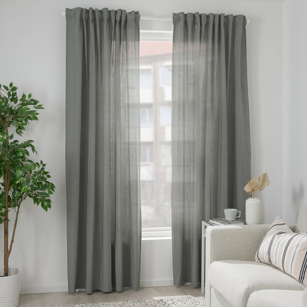 TIBAST grey room darkening curtains, made of cotton, hang behind white couch. They feature a subtle pattern and are larger than the plant beside them.