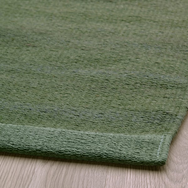 Close-up of a high-quality green rug, showcasing its soft texture and fine craftsmanship.