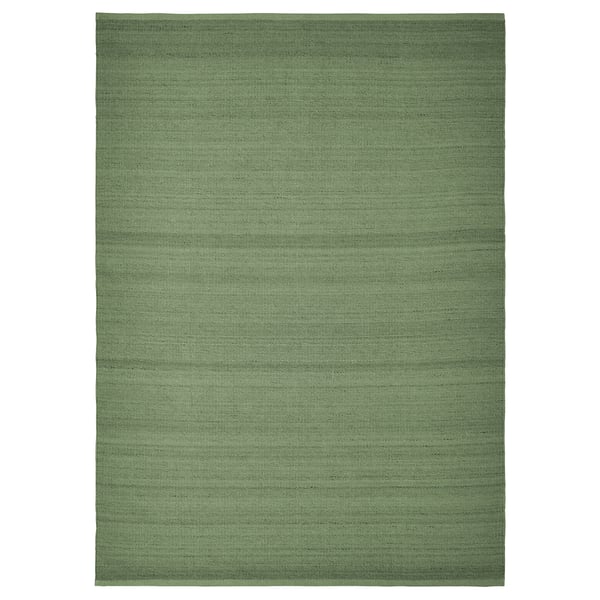 This image shows the TIDTABELL, a green rectangular rug with a wool surface and cotton backing. Its flatwoven and a subtle melange pattern.