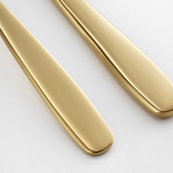 Two golden cake slices arranged diagonally, reflecting light with polished surfaces, on a plain white background.