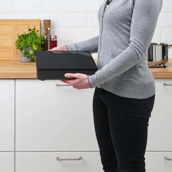 Person with induction cooktop in kitchen.