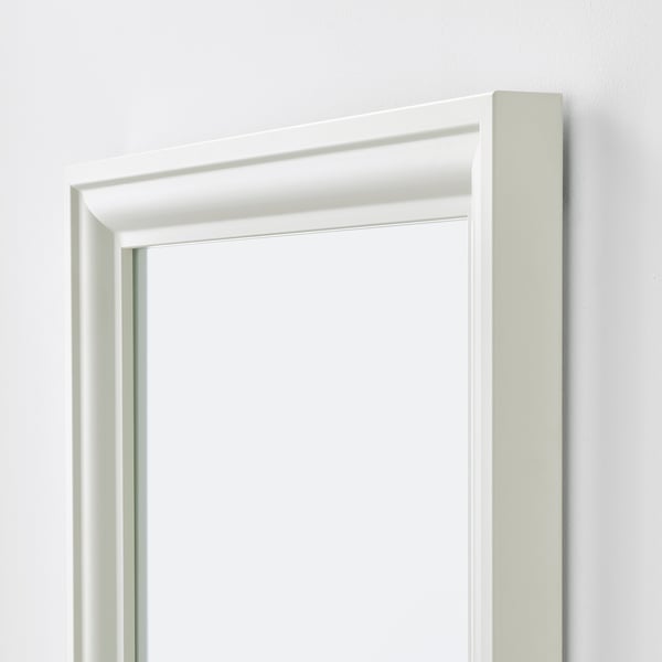 A white-framed mirror with a sleek design, positioned vertically, against a plain wall.