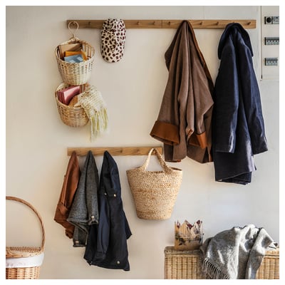 Wall with TOLKNING baskets, coats, towels, and a leopard print hat. Weaved from bamboo and rattan, creating a warm, organised space.