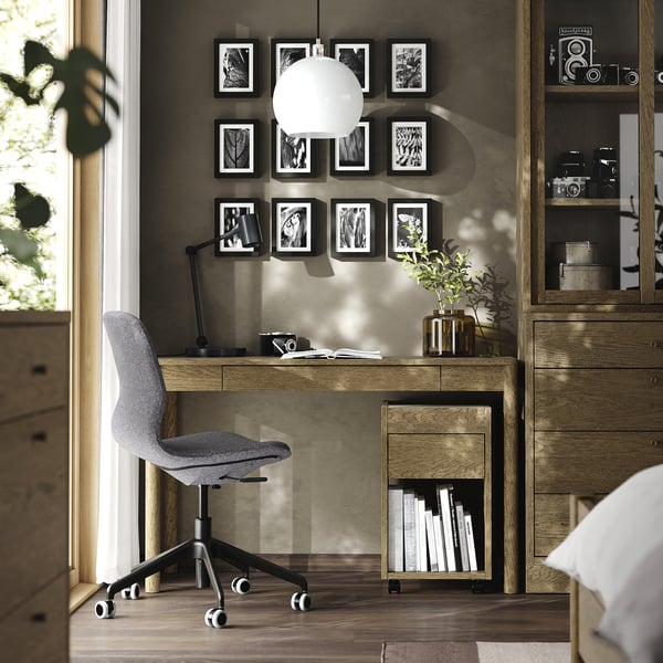 Modern home office with oak TONSTAD desk, grey chair, pendant light, and wall art.