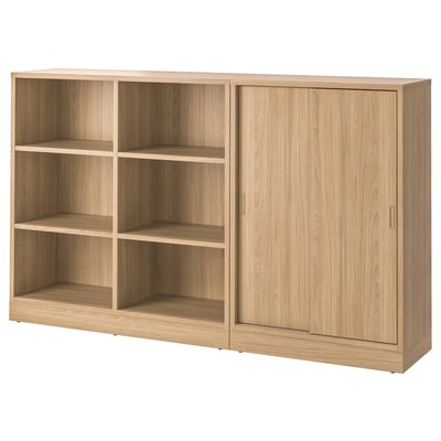A TONSTAD storage unit in oak finish with open and closed sections. It has adjustable shelves and a sliding door.