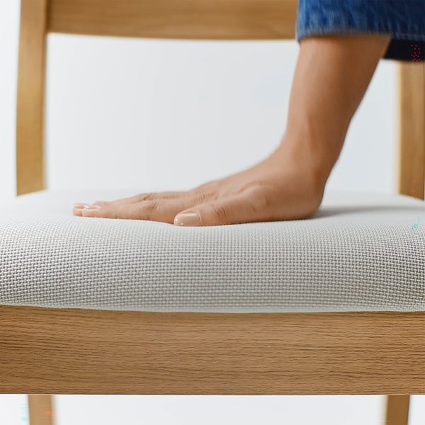 Bare foot comfortably touching soft, textured cloth surface of a sturdy, round-edged wooden chair, highlighting its premium quality and style.