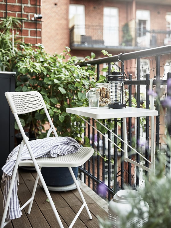 Small balcony setup with white TORPARÖ table and chair, potted plants.