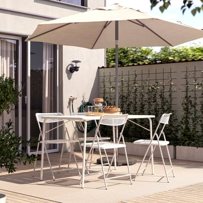 Backyard patio with beige TORPARÖ umbrella, white furniture, wooden table, and greenery.