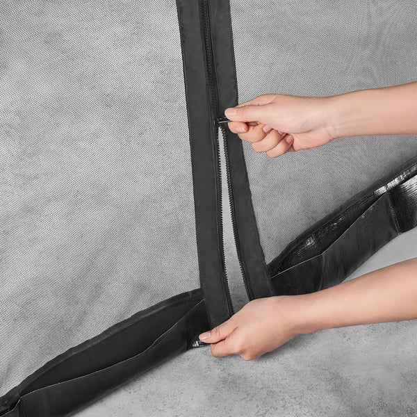 A person is zipping shut a TORPÖN insect net, which attaches to a parasol, creating a sealed, insect-free space.