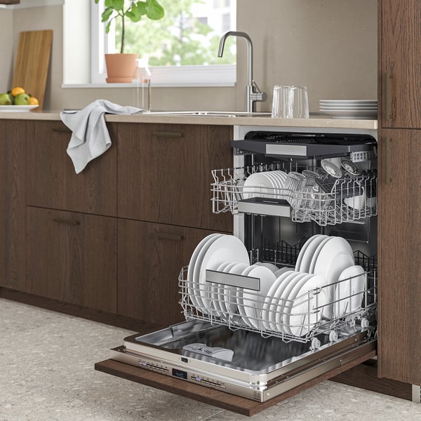 A modern kitchen with dark wooden TORSBODA dishwasher, filled with dishes, open beside brown cabinets.