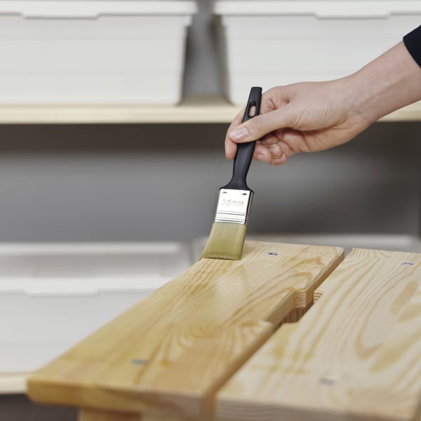 Hand brushes wooden board with protective oil, enhancing its shine and durability.