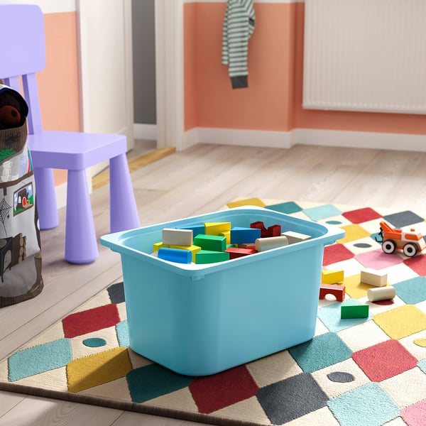 Light blue TROFAST storage bin on colourful rug with building blocks.