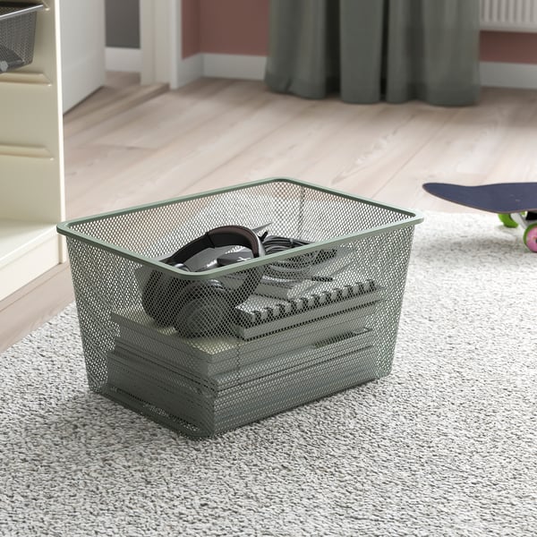 Metal mesh storage basket holds items like headphones, sits on carpeted floor, ideal for teen rooms.