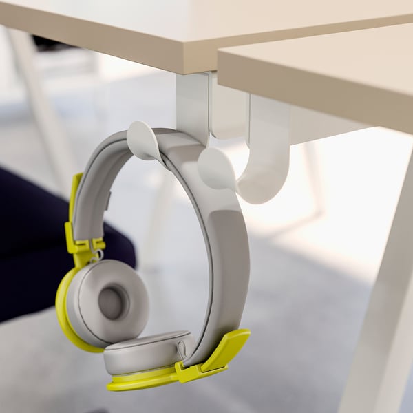 Yellow and grey headphones hung on white TROTTEN desk hooks.