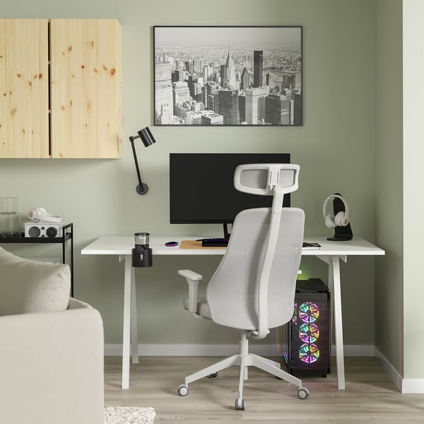 Stylish home office with TROTTEN chair, desk, shelves, and green wall. Modern decor with cityscape art and black lamp.