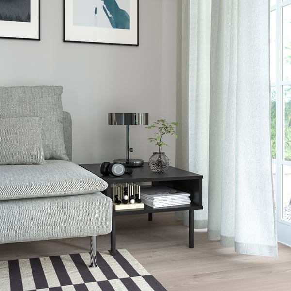 Modern living room with grey sofa, black TUNSTA side table, lamp, plant, and window with curtains.