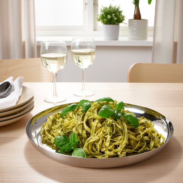 Plated pasta dish with wine glasses on a wooden table.