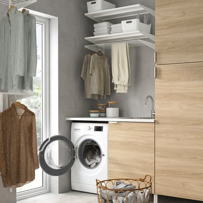 Modern laundry room with UDDARP appliances, cabinets, sink, storage, & folded clothes.