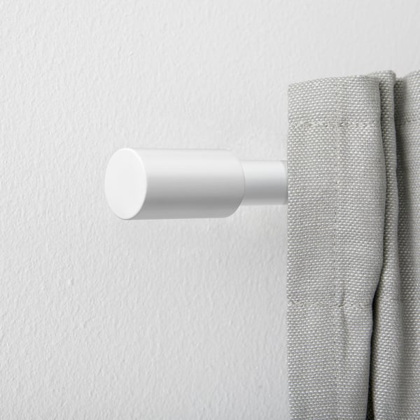 White finials on curtain rod, minimalist design.