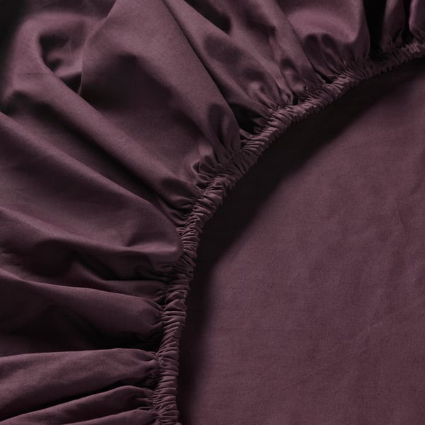 Close-up of luxurious, dark purple bed sheet. Elastic edges and smooth texture visible, highlighting quality.