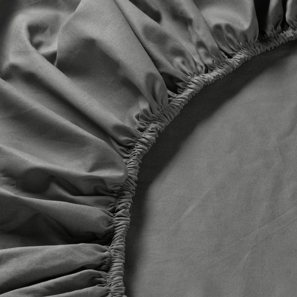 Close-up of soft, high-thread-count bed sheet with elastic edging, showcasing smooth texture and quality.