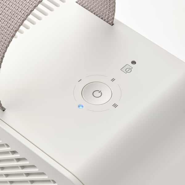 Top view of a sleek, white air purifier with a circular power button and indicator light on a smooth surface.