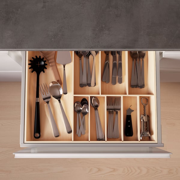 Organized kitchen drawer with bamboo UPPDATERA cutlery tray, storing silver and black utensils.