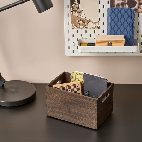 Wooden box on desk holds notebooks and papers, organised for workspace.