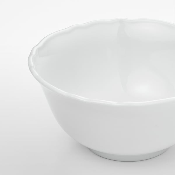 Smooth, white porcelain bowl with ruffled edge; simple, elegant design. Ideal for food or decoration.