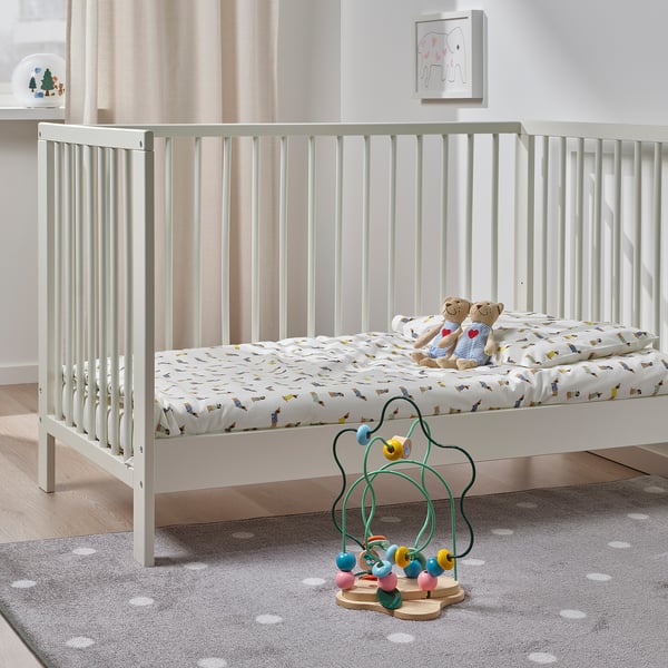 Crib with teddy bear & colorful bead maze toy UPPSTÅ on rug.