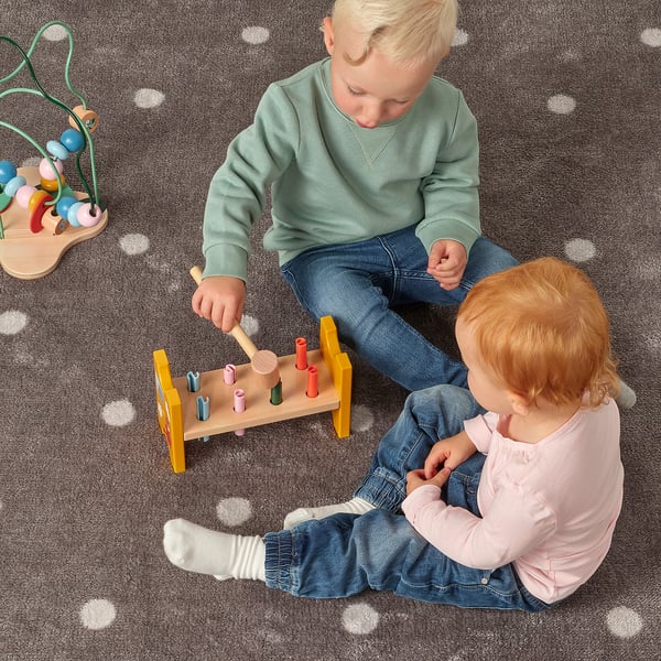 Kids play with UPPSTÅ hammering block. Boy hammers plugs, girl watches.