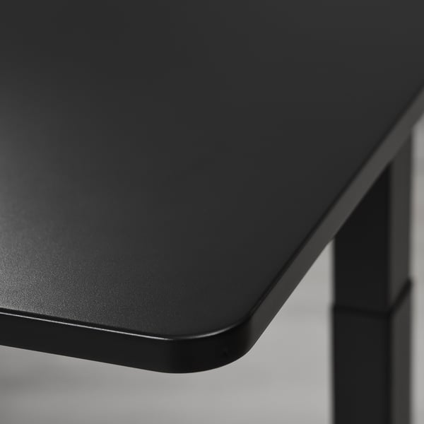 Black gaming desk with smooth, deep surface; sturdy edge detail, polished finish.