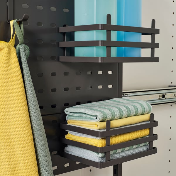 Black pull-out shelves hold neatly folded towels, making them easily accessible and organised within a cabinet.