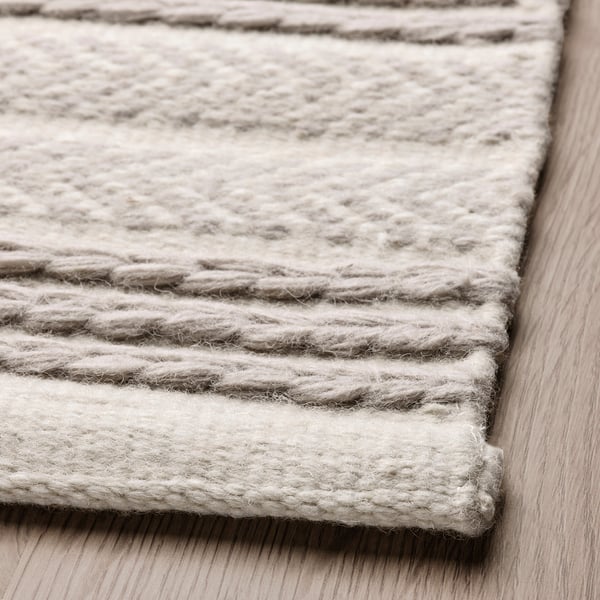 Close-up of finely woven wool rug with horizontal grey and cream stripes, neat soumak borders.