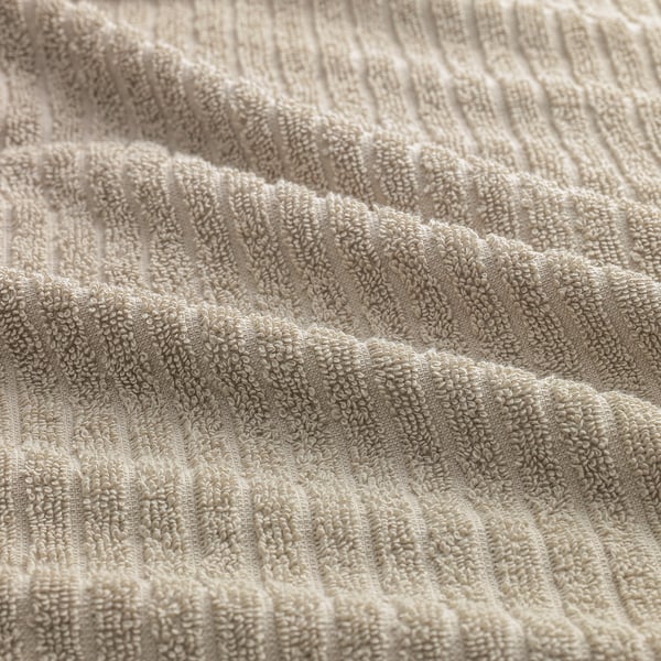 Folded beige towels with textured, striped pattern, suggesting softness and absorbency.