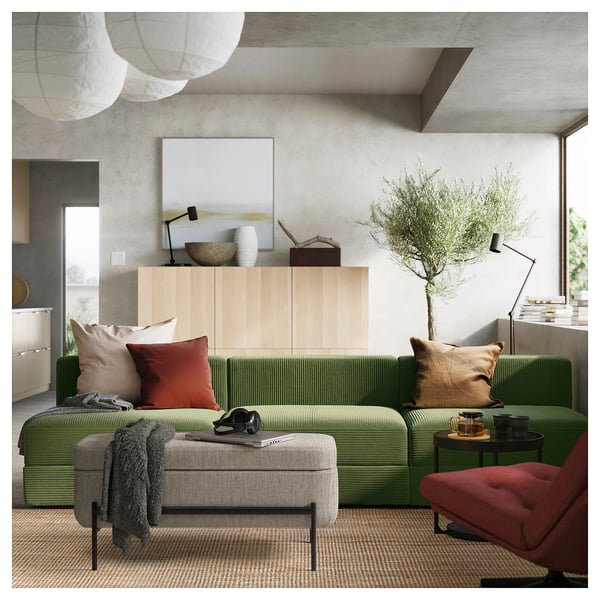 Modern living room with green VALTORP sectional sofa, wooden cabinet, and hanging lamps.