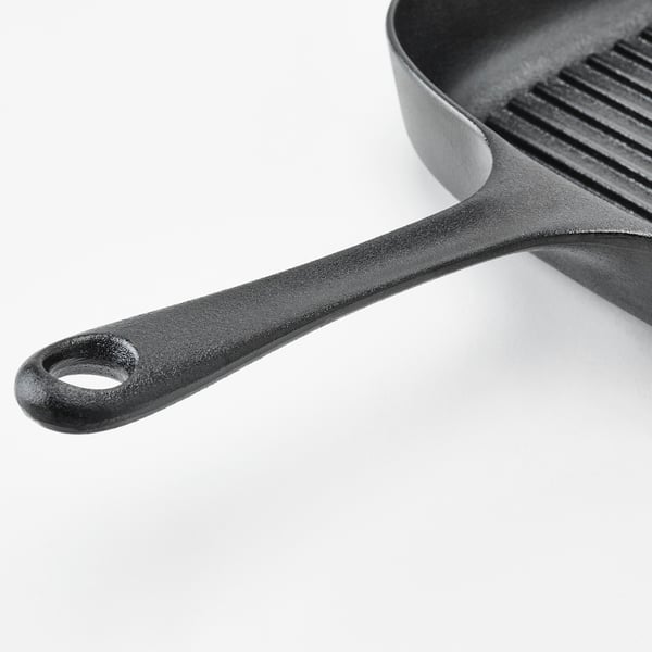 Close-up of a cast iron pan handle, showing its sturdy and well-constructed design.