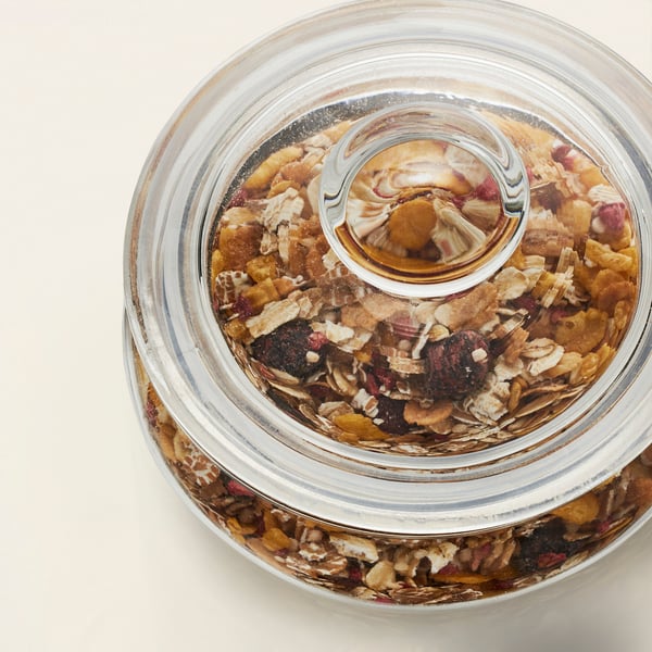 Clear glass jar displays homemade cookies, showcasing contents, with a non-airtight lid.