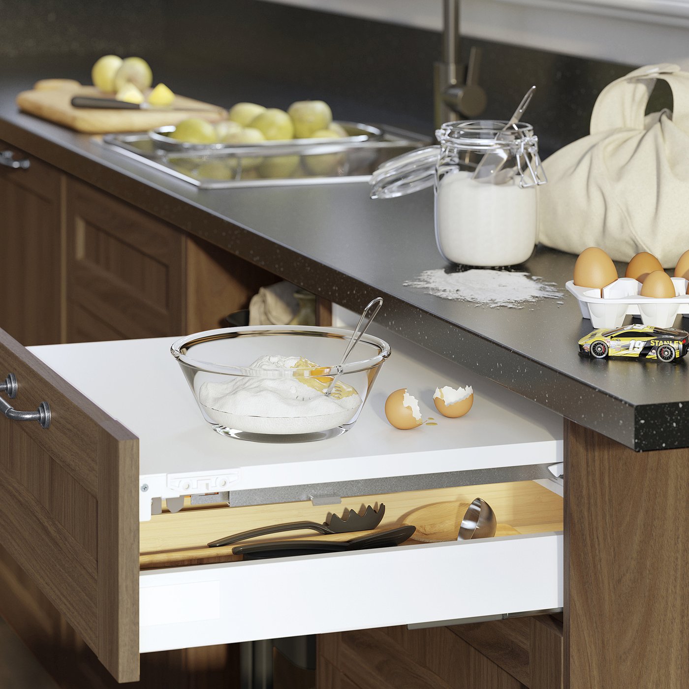 Kitchen counter with VARDAGEN bowl of sugar, apples, boards, toy car, and open drawer of spatulas.