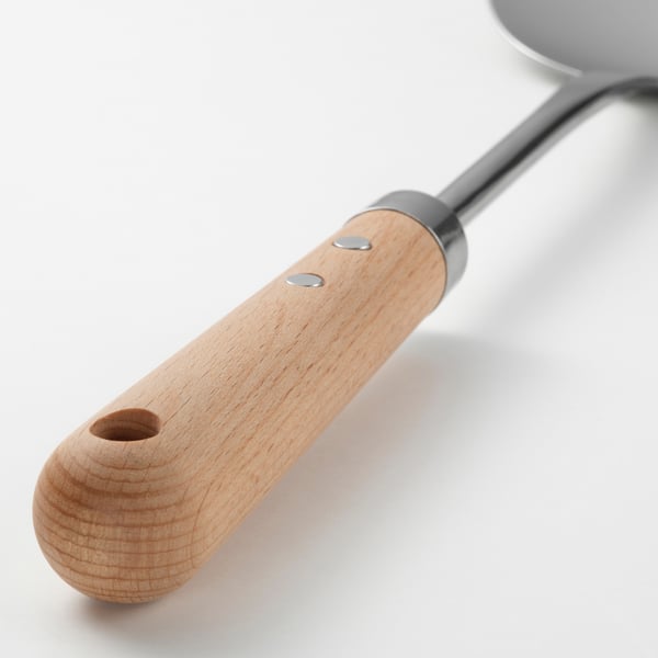 Close-up of wok spatula with wooden handle, metallic shaft, and hanging hole for storage.