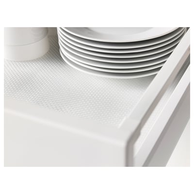 Stacked white plates on a textured drawer mat. The mat dampens sounds and protects surfaces.