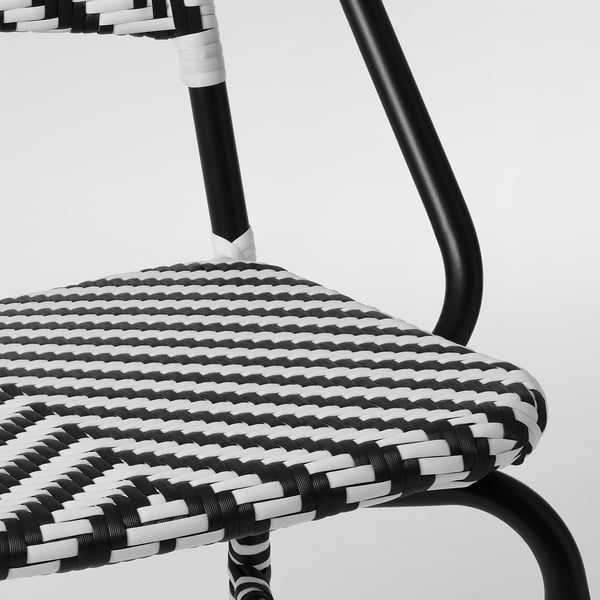 Black and white woven chair with curved metal frame, meticulously crafted, showcasing high-quality design and durability.
